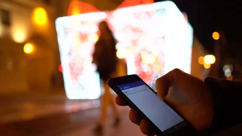 Closeup of young man hands scrolling internet on phone. Night illuminated city Stock Footage 69073211