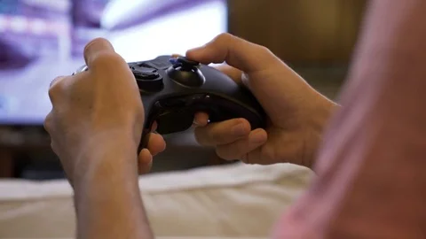 Closeup of young man hands using joystick playing video games on large TV scr Stock Footage