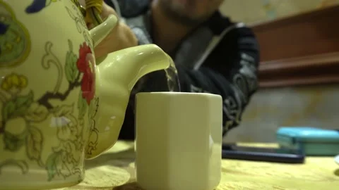Closeup of a young man serving tea from a hot teapot in small white china 스톡 동영상 161446950