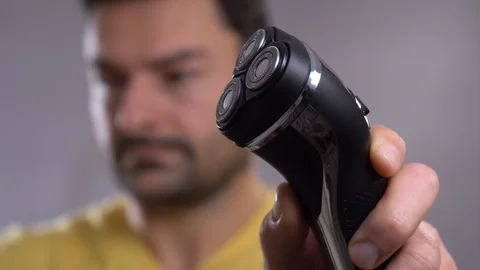A closeup of a young man shaving his beard off with an electric shaver. Video stock 101710943