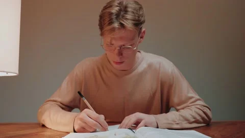Closeup of young man studying at home writing in his notes, reading a textbook 스톡 동영상 164371933