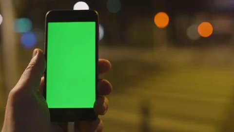 Closeup. Young man is using Smartphone with Green Screen at Evening Time in Stock Footage 73839742