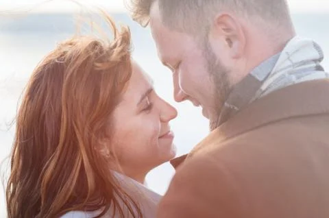 Closeup of young pair faces man and woman in coat looking each other outdoor Foto stock