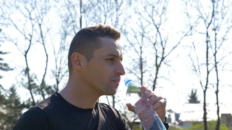 Closeup of young thirsty athlete drinking water from bottle after workout Stock Footage 77737695