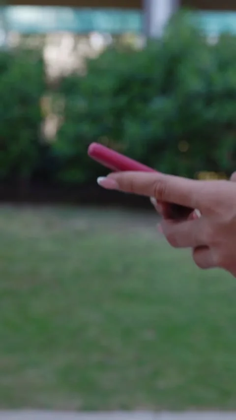 Closeup of young woman hands using mobile phone walking at city street. Vidéo 309034149