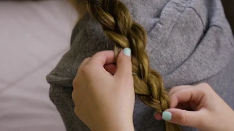 Closeup Of Young Woman's Hands, Completing A Braid On Her Friend, Inside Video stock 71270490