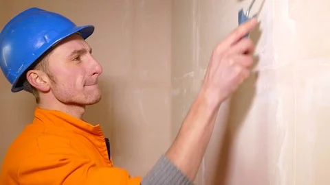 Closeup of Young worker in helmet working with paint roller Stock Footage 71940870