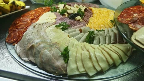 Closeup zoom in at assortment of cheese, bacon, and salami slices at food court Stock Footage 143488367
