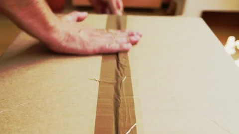 Closing a box with brown tape on the moving out day Packing to move out Stock Footage 157437680