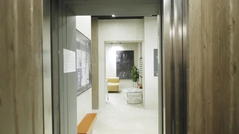 Closing metallic doors of elevator reflects passenger Видео 330990017