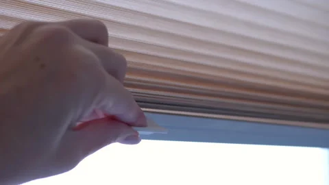Closing pleated blinds on window Stock Footage 312010929