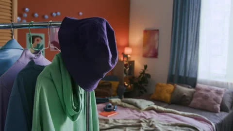 Closing Rack with Purple Bucket Hat, Green Hoodie and Other Items in Bedroom Vídeo Stock 298591043