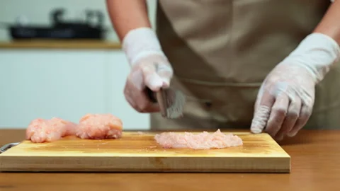 Closup of gloved hands mincing raw chicken on wooden board, showcasing food.. Stock Footage 312980375