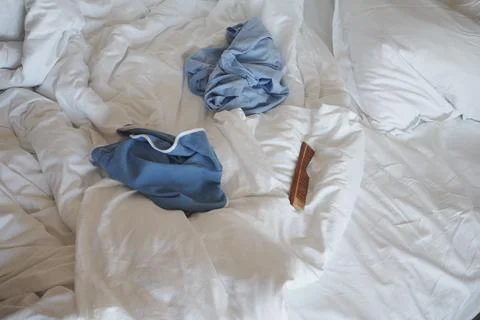 Clothes and a comb on a messy bed in a room 스톡 사진