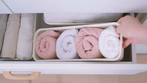 Clothes and towels in plastic containers in closet top view, space organization Vidéo 169590126
