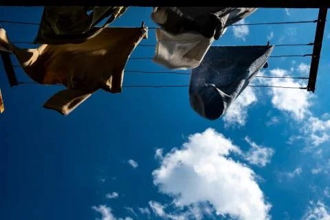 Clothes are dried on the wind on background blue sky and clouds. Photos