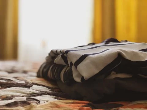 The clothes are stacked on the bed. Stock Photos