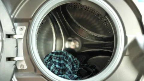 Clothes being tossed into the washing machine to prepare for cleaning Видео 308840659