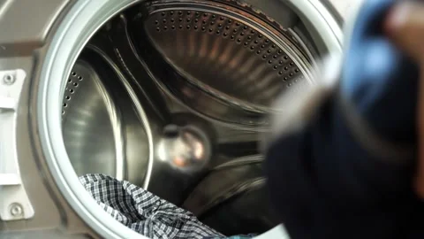 Clothes being tossed into the washing machine to prepare for cleaning Видео 308840660
