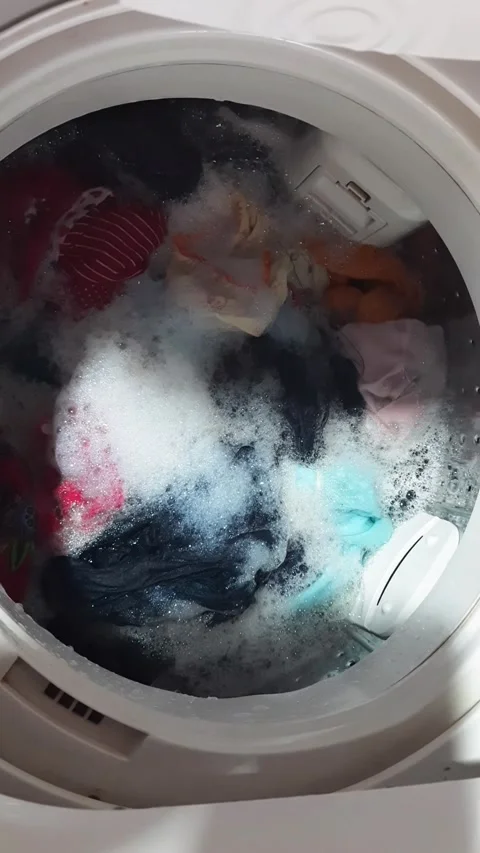 Clothes being washed in a top loading washing machine with soap and water Video stock 322009046
