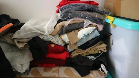 Clothes creating a messy pile in a corner, depicting disorganization, stora.. Stock Photos