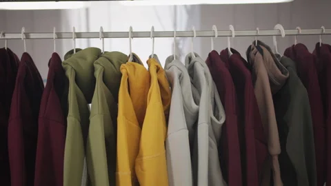 Clothes of different colors hang on a hanger in a bright room Stock Footage 244732944