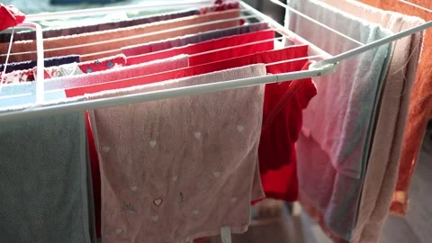 Clothes drying on a clothes rack, bathed in soft natural light. The neatly arran Stock Footage 301106681