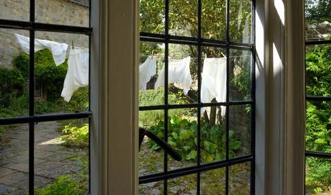 Clothes drying in the garden seen through a window Stock Photos