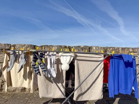 Clothes drying on rack outdoors under a blue sky with contrails, concept of h Foto stock