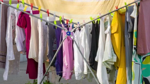 Clothes drying rack on sunny and windy day - colorful laundry hanging. Stock Footage 270436739