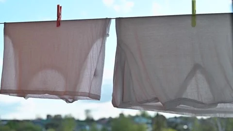 Clothes hang on a clothesline under a clear sky. Bright sunlight shines on the Stock Footage 336778776