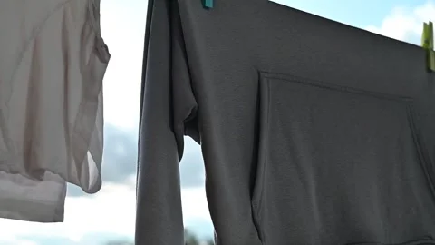 Clothes hang on a line under a blue sky with clouds. Light shines through the 스톡 동영상 336778787