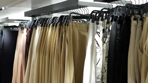 Clothes hang on rack in store, showing variety. Each rack holds fashionable Stock Footage 279656600