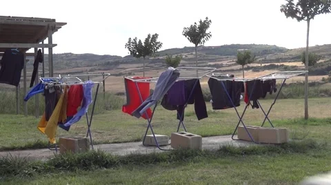 Clothes hanged out to dry on a clothes dryer, a cottage somewhere Stock Footage 59657179