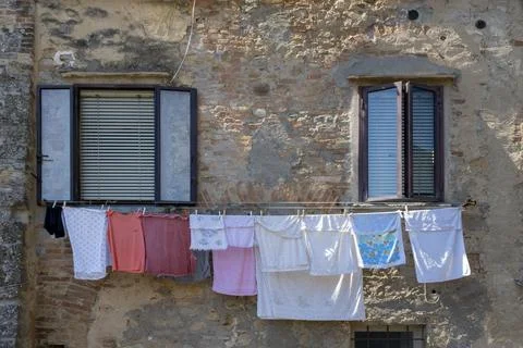 Clothes hanging under a window on a brick wall Stock Photos