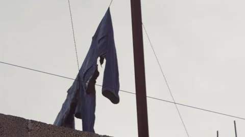 Clothes hanging from a wire on a line, swaying in the air. Video stock 285154708