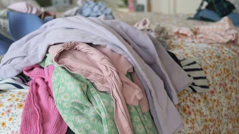 Clothes piled on bed in messy bedroom Stock Footage 323338351