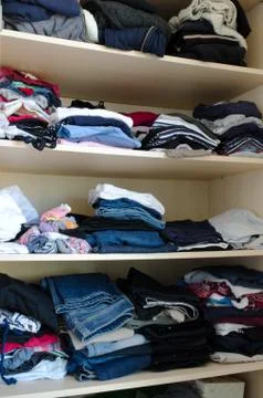 Clothes in piles in a wardrobe Stock Photos
