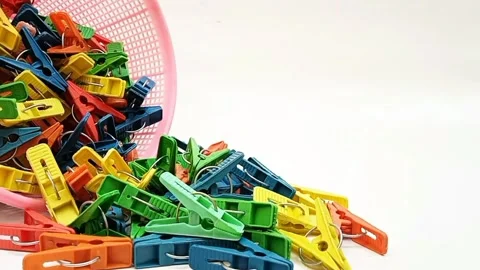 Clothes pins falling out of a basket moving on the white background,  Video stock 306340125