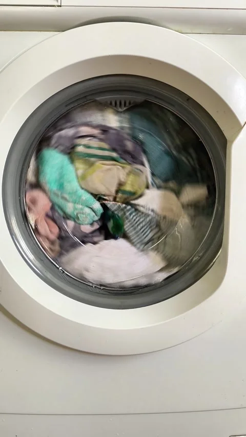 Clothes spinning in washing machine drum, laundry cycle in process, Stock Footage 335885373