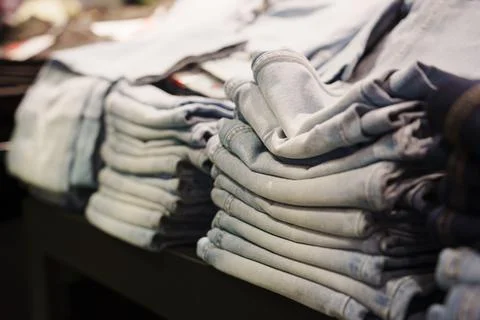Clothes store displays stacks of folded denim jeans on table Stockfoto's