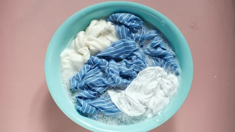 Clothes washed with basin with soap bubbles close-up on a pink background, top Stock Footage 301842804