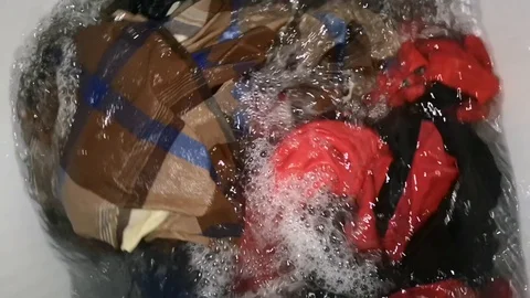 Clothes in a washing machine with soap bubbles. washing machine is in operation. Stock Footage 113295394