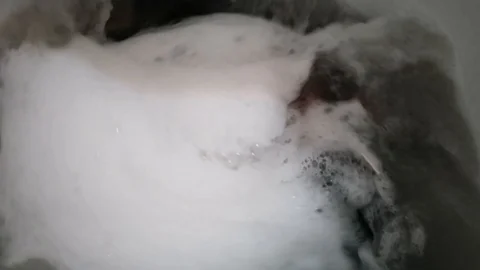 Clothes in a washing machine with soap bubbles. washing machine is in operation. Stock Footage 113295514