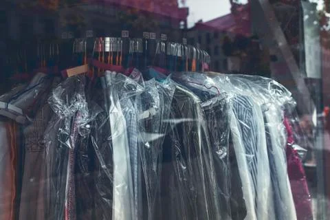 Clothes wrapped with plastic on a rack in the window of a laundry Stock Photos