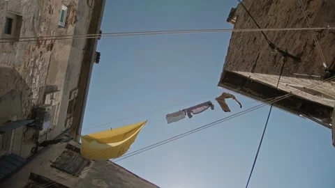 Clothesline between houses against a blue sky Vidéo 247450053