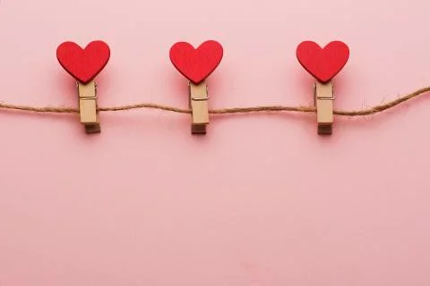 Clothespins with hearts on a rope on a red background Stock Photos