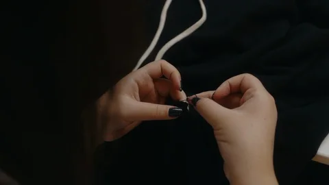 A clothing designer ties knots of thread on sewn clothes Stock Footage 129606872