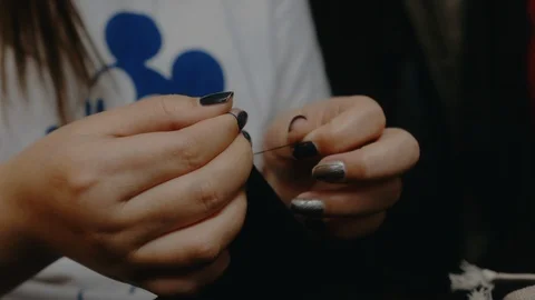 A clothing designer ties knots of thread on sewn clothes Stock Footage 129606904