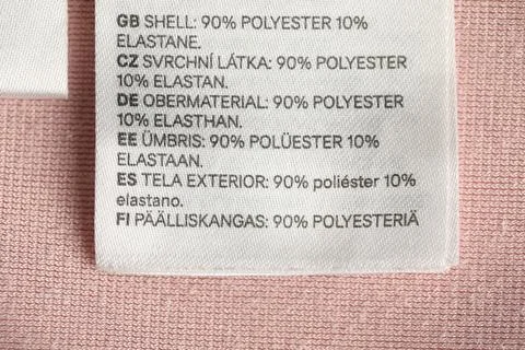 Clothing label in different languages on light pink garment, closeup Stock Photos